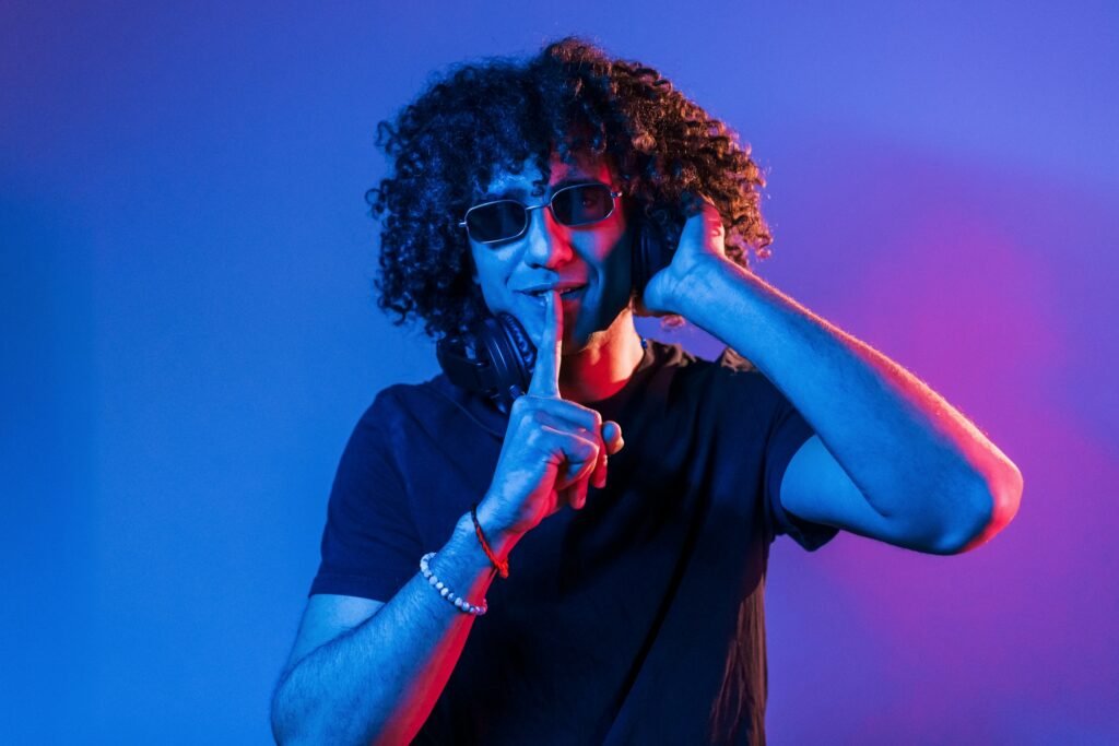 Young Beautiful Man With Curly Hair Is Indoors In The Studio With Neon Lighting 1024x683
